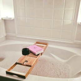 a bathtub with a book and drink
