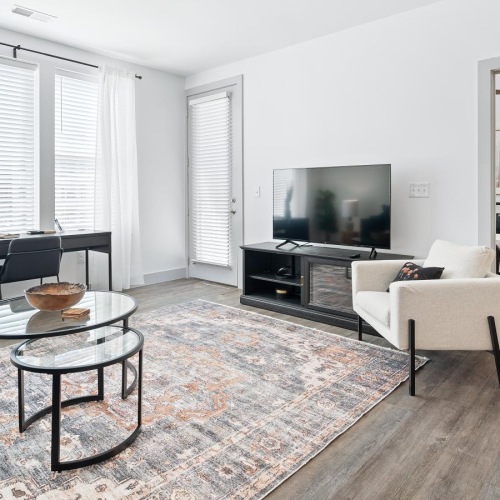 a living room with a tv, tables, chairs and a couch
