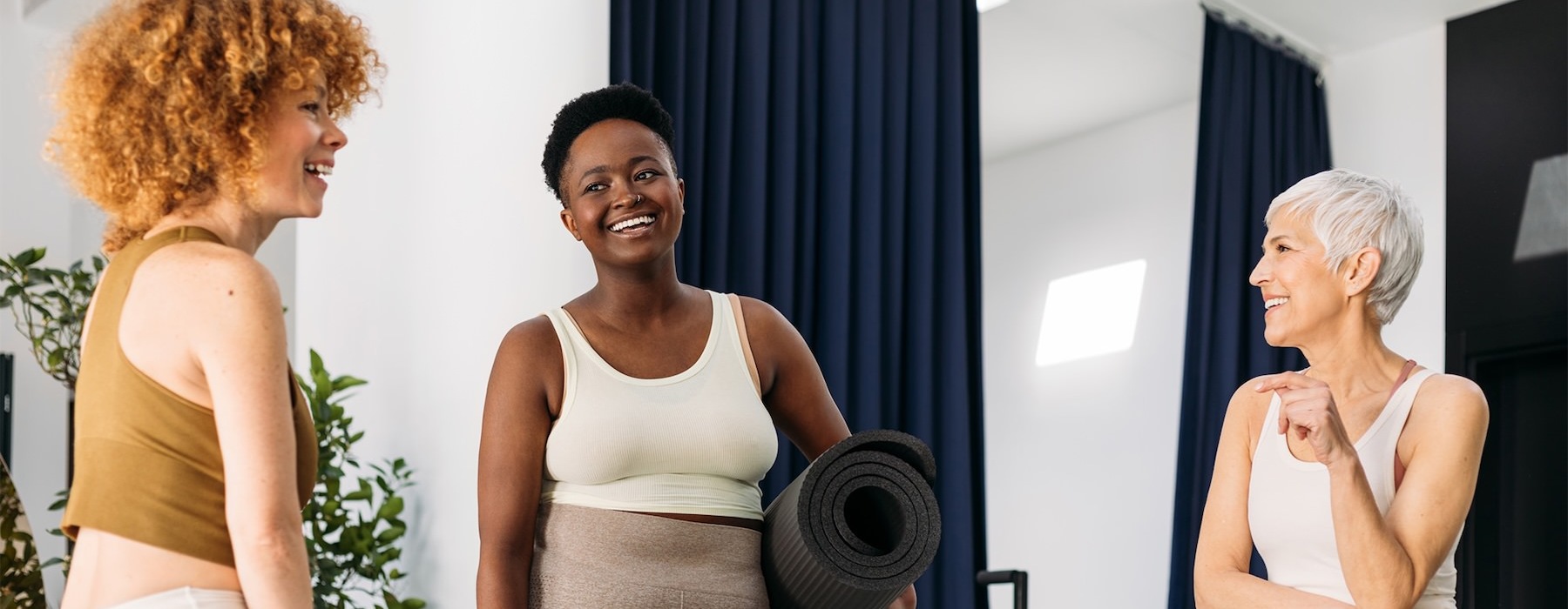 a person holding a yoga mat standing next to a person sitting on a chair